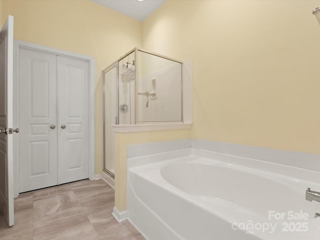 bathroom featuring baseboards, a shower stall, and a garden tub