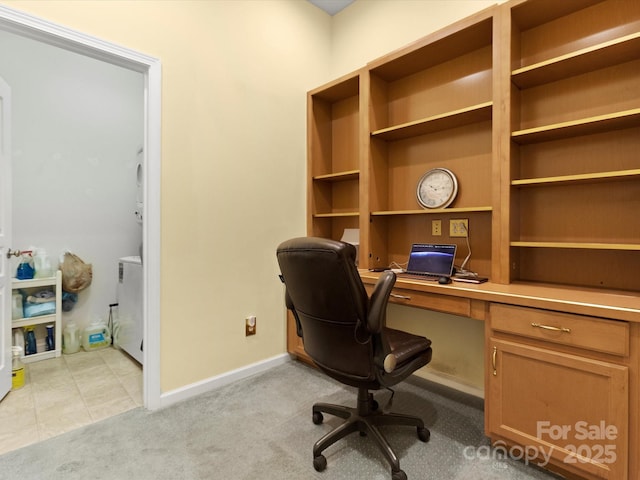 office space featuring baseboards, light carpet, and built in study area