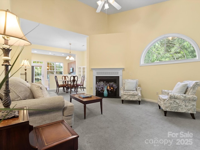 living room with carpet floors, ceiling fan, a fireplace with flush hearth, and a healthy amount of sunlight