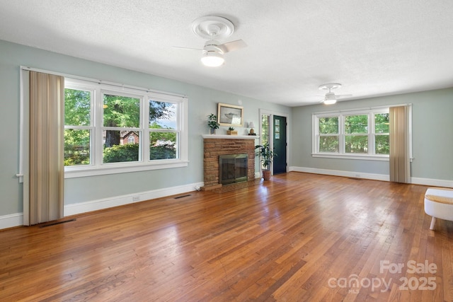 3418 Sulphur Springs Rd NE, Hickory, NC 28601 - unfurnished living room with ceiling fan, a glass covered fireplace, wood finished floors, baseboards, and a textured ceiling