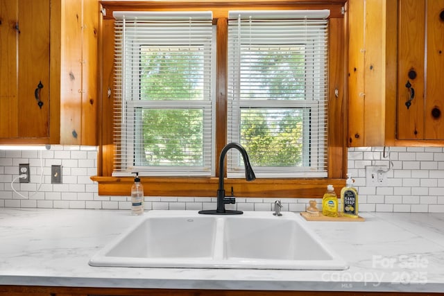 3418 Sulphur Springs Rd NE, Hickory, NC 28601 - kitchen view of a sink, backsplash, brown cabinetry, and light stone counters