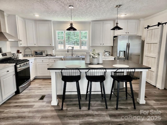 2025 Kisatchie Dr, Hickory Grove, SC 29717 - kitchen featuring appliances with stainless steel finishes, wall chimney range hood, a barn door, a kitchen island, and a sink
