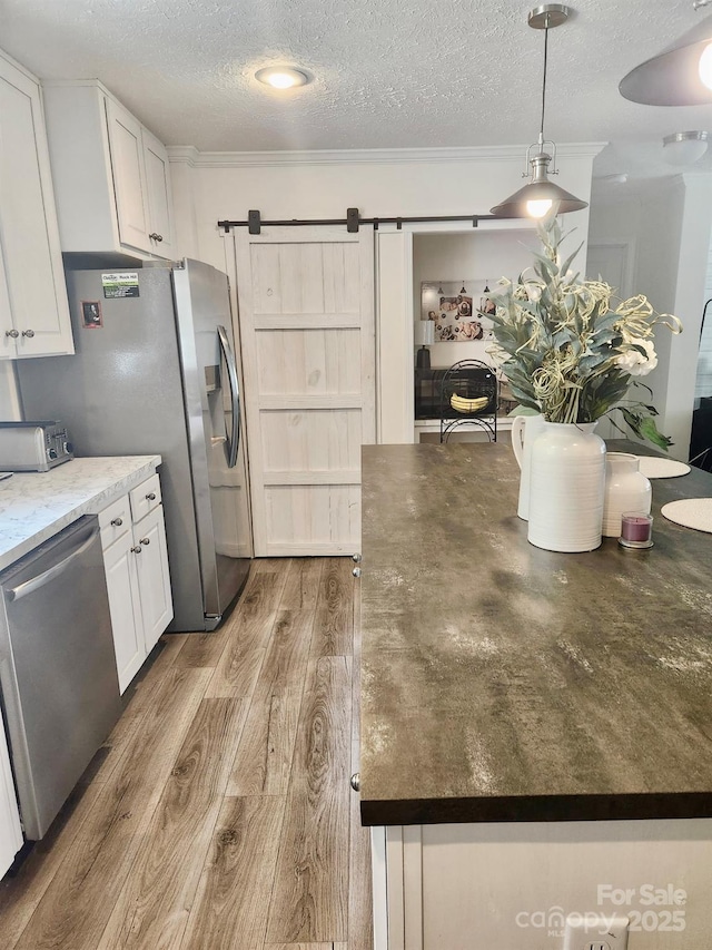 2025 Kisatchie Dr, Hickory Grove, SC 29717 - kitchen with stainless steel appliances, a textured ceiling, a barn door, white cabinetry, and wood finished floors