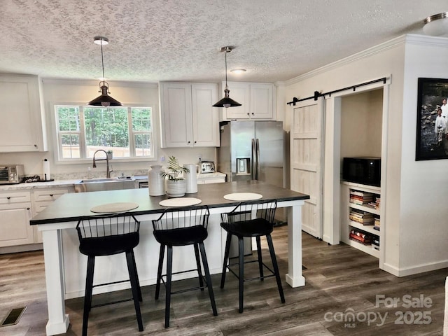 2025 Kisatchie Dr, Hickory Grove, SC 29717 - kitchen with a sink, black microwave, a barn door, stainless steel fridge with ice dispenser, and dark wood-style floors