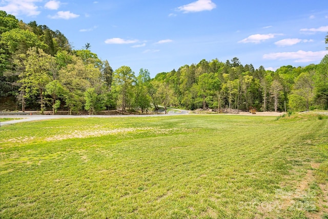 surrounding community featuring a yard and a wooded view