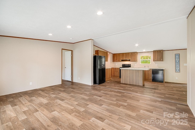 kitchen featuring black appliances, light countertops, brown cabinets, light wood-style flooring, and open floor plan