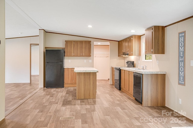 kitchen with black appliances, ornamental molding, light wood-style flooring, light countertops, and a kitchen island