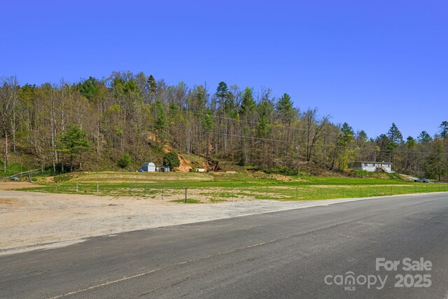 view of asphalt street featuring a view of trees