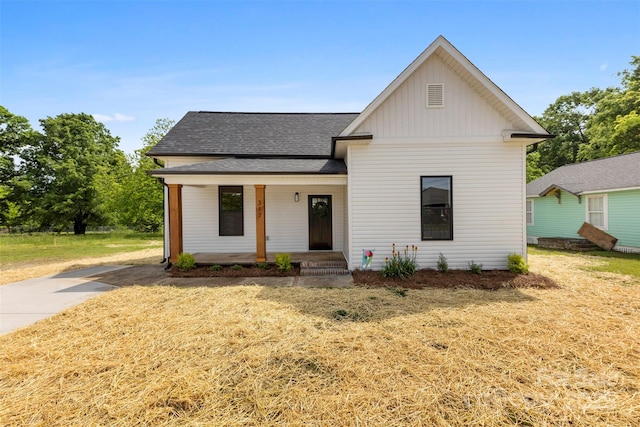modern inspired farmhouse featuring covered porch, board and batten siding, roof with shingles, and a front lawn