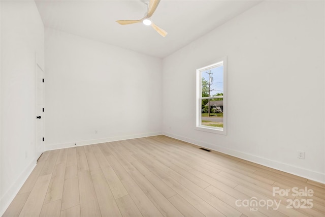 spare room featuring light wood-style floors, baseboards, and ceiling fan