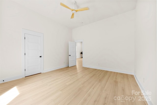 spare room featuring light wood-type flooring, a ceiling fan, and baseboards