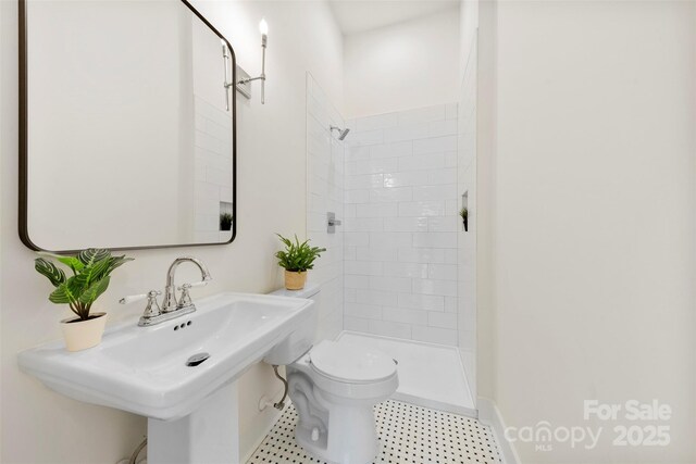 bathroom featuring toilet, a sink, and tiled shower