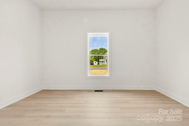 unfurnished room featuring light wood-type flooring, baseboards, and visible vents