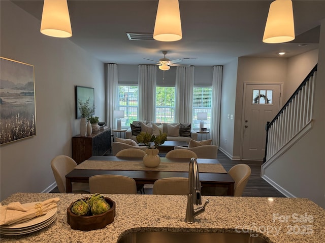 dining space featuring visible vents, stairs, wood finished floors, baseboards, and a ceiling fan