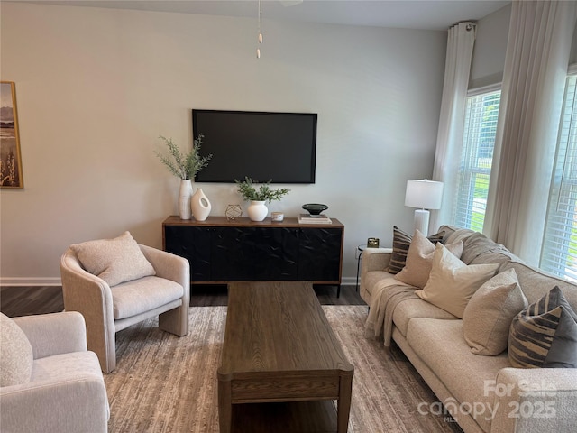 living room featuring baseboards, a healthy amount of sunlight, and wood finished floors