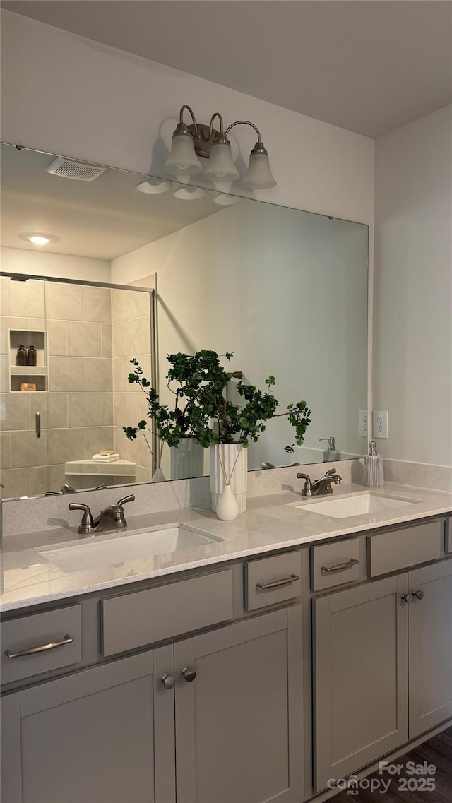 bathroom with double vanity, a sink, and a tile shower