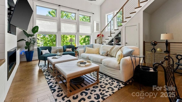 living area with stairs, a towering ceiling, and hardwood / wood-style floors