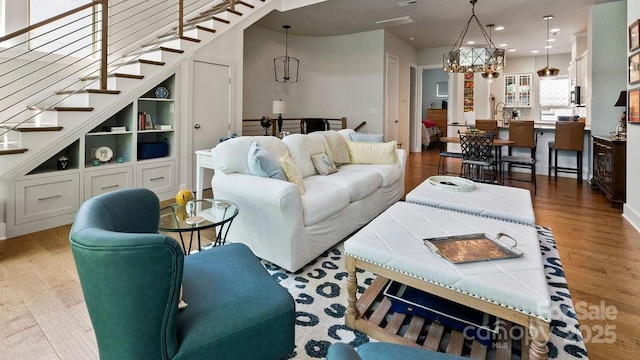living area featuring recessed lighting, stairs, wood finished floors, and a notable chandelier