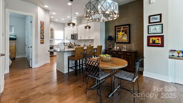dining room with baseboards, recessed lighting, wood finished floors, and an inviting chandelier
