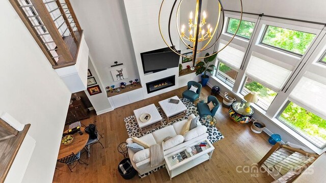 living room featuring a high ceiling, a chandelier, plenty of natural light, and wood finished floors