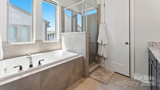 bathroom with tile patterned flooring, a shower stall, a garden tub, and vanity