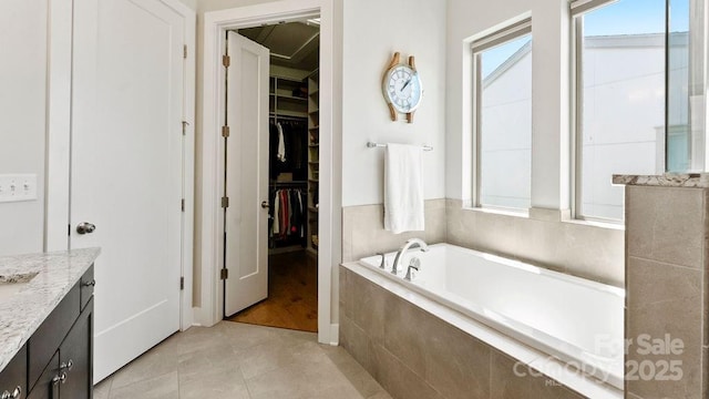 bathroom with tile patterned flooring, a walk in closet, a bath, and vanity