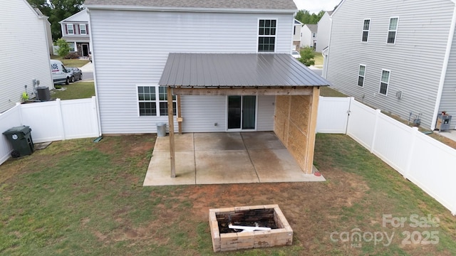 back of property with a lawn, metal roof, a patio area, roof with shingles, and a fenced backyard