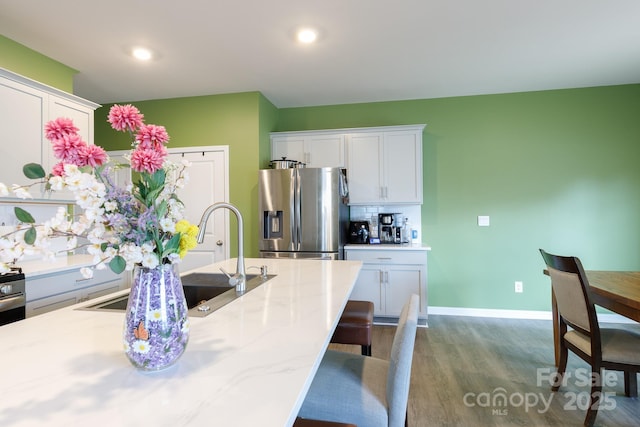 kitchen with a breakfast bar, baseboards, backsplash, dark wood-style floors, and stainless steel fridge with ice dispenser