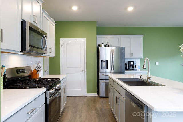 kitchen with a sink, dark wood-type flooring, light countertops, appliances with stainless steel finishes, and tasteful backsplash