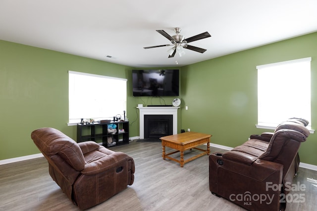 living area featuring baseboards, a fireplace, visible vents, and plenty of natural light