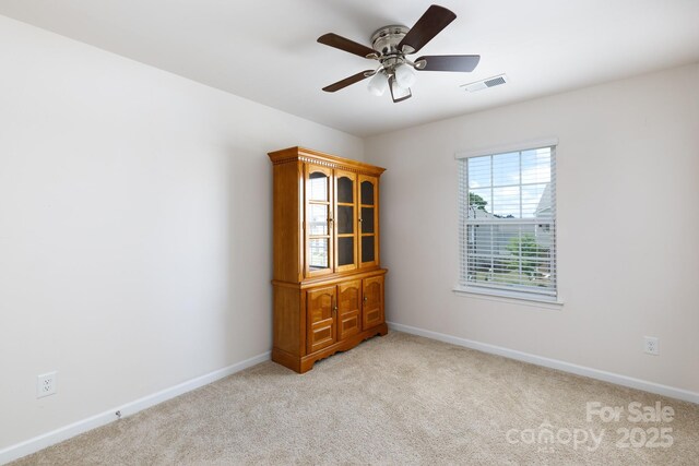 unfurnished room featuring light colored carpet, visible vents, baseboards, and ceiling fan