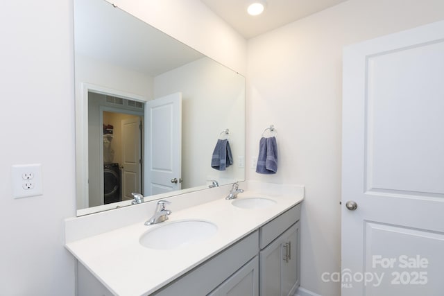 bathroom with a sink, double vanity, and washer / dryer