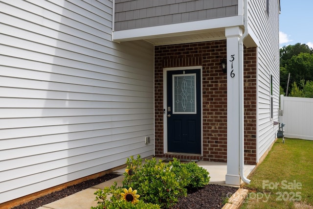 property entrance with brick siding and fence