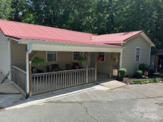 view of front of house with covered porch, metal roof, and aphalt driveway