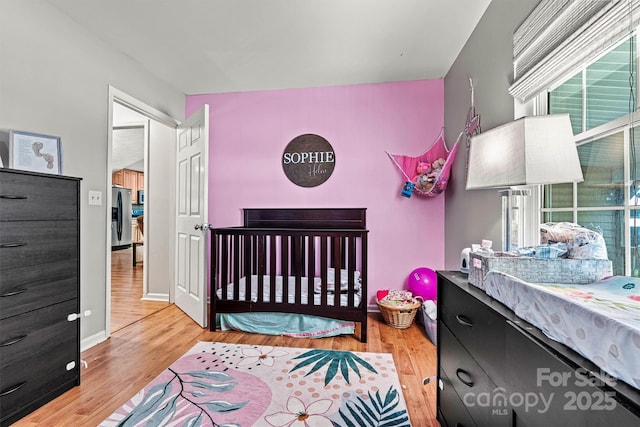 3690 Birchwood Ln, Denver, NC 28037 - bedroom featuring stainless steel fridge with ice dispenser, wood finished floors, and a crib