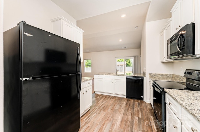 kitchen with light stone countertops, light wood-type flooring, black appliances, a peninsula, and white cabinetry