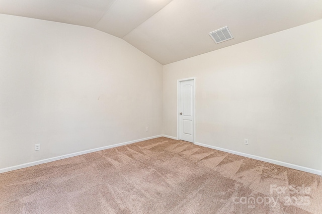 unfurnished room with visible vents, baseboards, vaulted ceiling, and light carpet