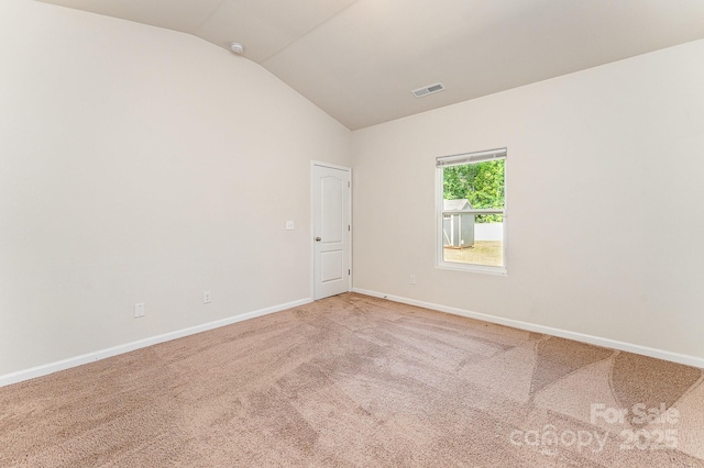 carpeted empty room with baseboards, vaulted ceiling, and visible vents