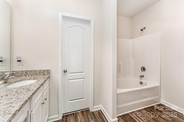 full bath with baseboards, shower / tub combination, wood finished floors, and vanity