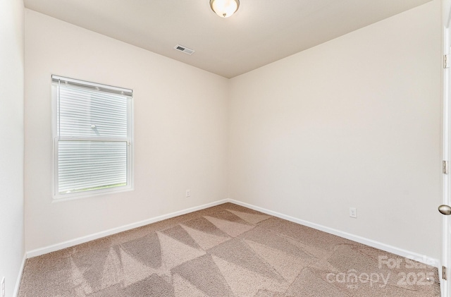carpeted empty room featuring baseboards and visible vents