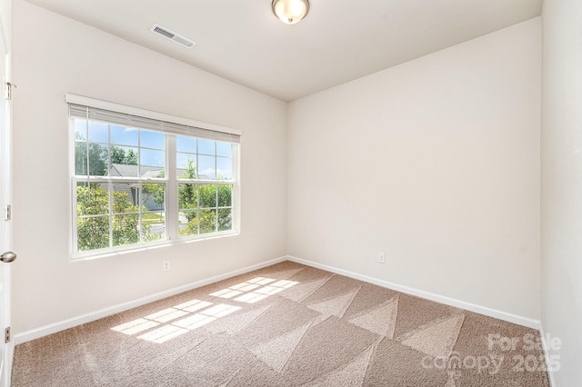 carpeted spare room featuring visible vents and baseboards