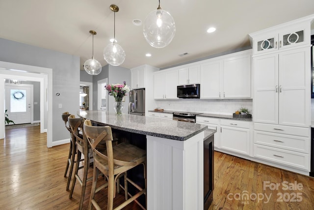 3426 Richards Xing, Fort Mill, SC 29708 - kitchen with appliances with stainless steel finishes, decorative backsplash, an island with sink, white cabinets, and light wood finished floors