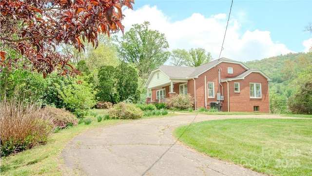 view of front of property featuring brick siding, cooling unit, a front lawn, and aphalt driveway