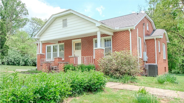 view of front of house featuring central AC unit, a shingled roof, and brick siding