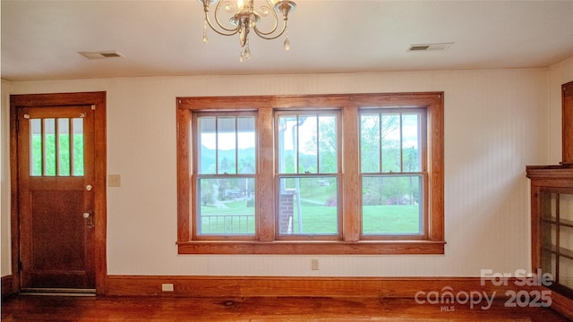 interior space featuring visible vents, baseboards, a notable chandelier, and dark wood finished floors