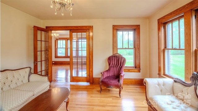living area with baseboards, an inviting chandelier, and light wood-style flooring