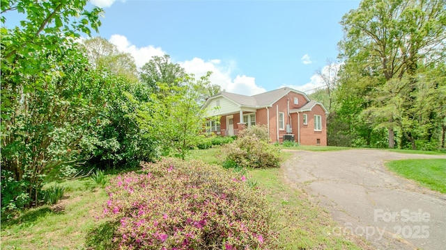view of front of home with brick siding, a front yard, and aphalt driveway