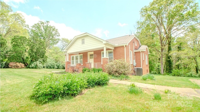 view of front facade with brick siding, central AC unit, and a front yard