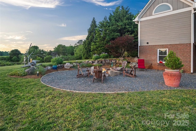 yard at dusk with a lawn, a fire pit, and a patio