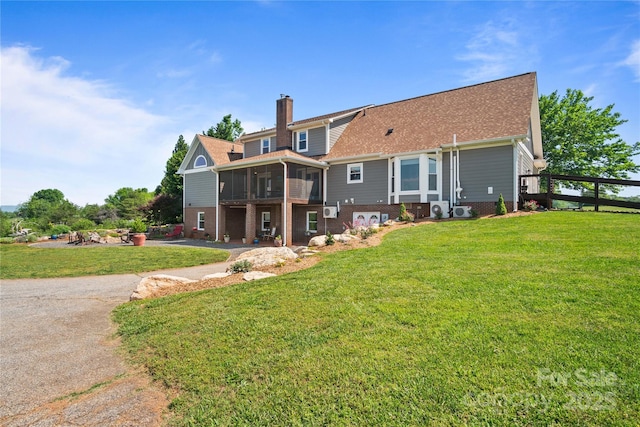 back of property with a sunroom, a chimney, and a lawn